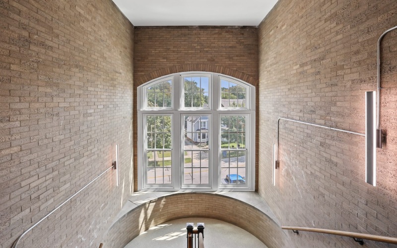 a staircase with a large window and brick walls