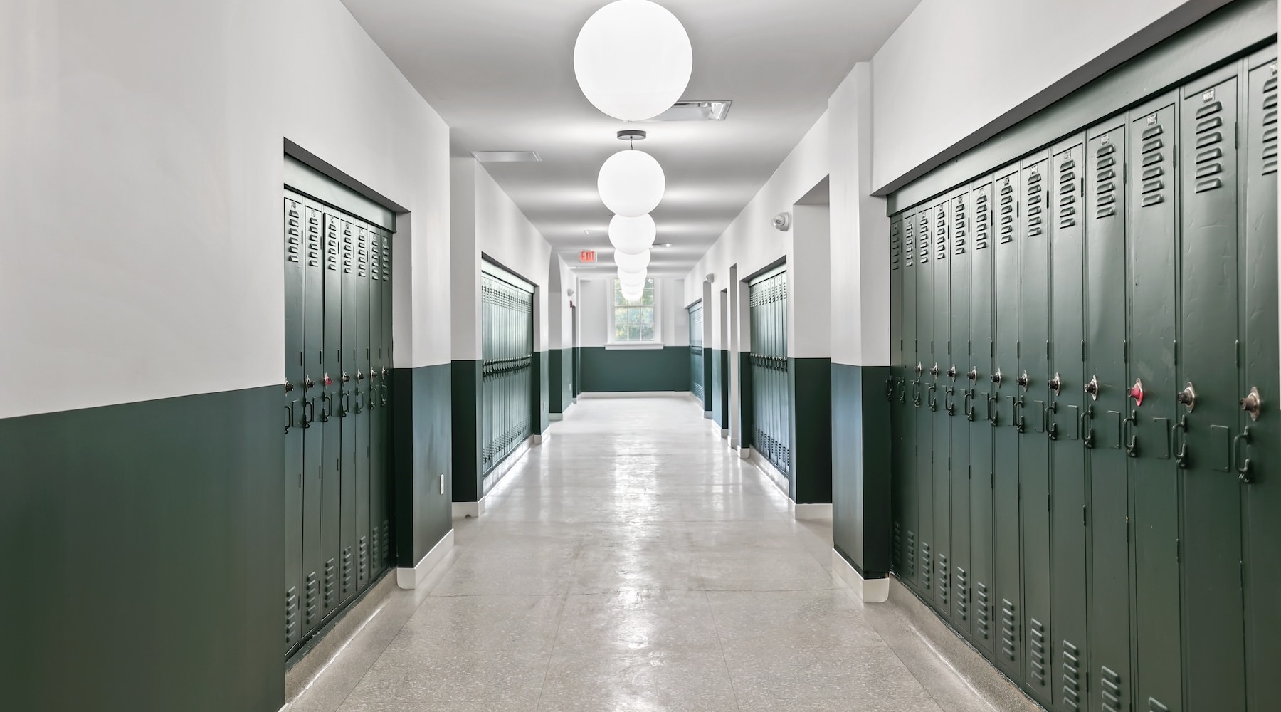 a hallway with green lockers and a window at the end